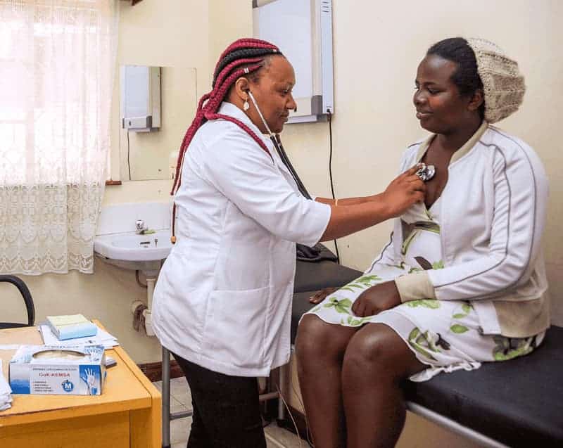 Doctor examining a patient with a stethoscope in a clinic setting.