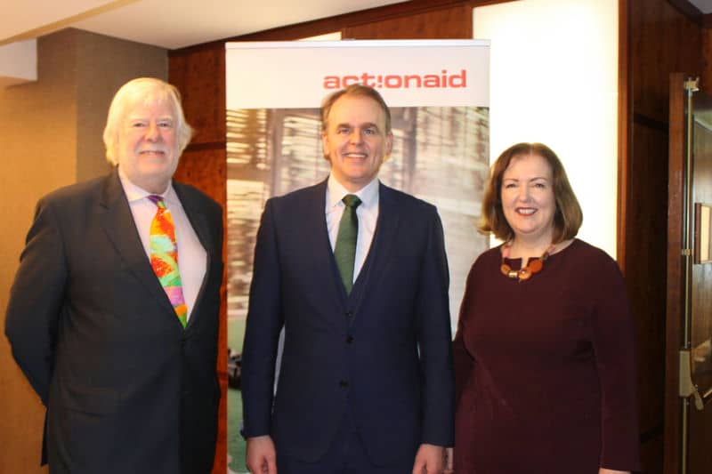 Three people standing in front of an ActionAid banner at an event.