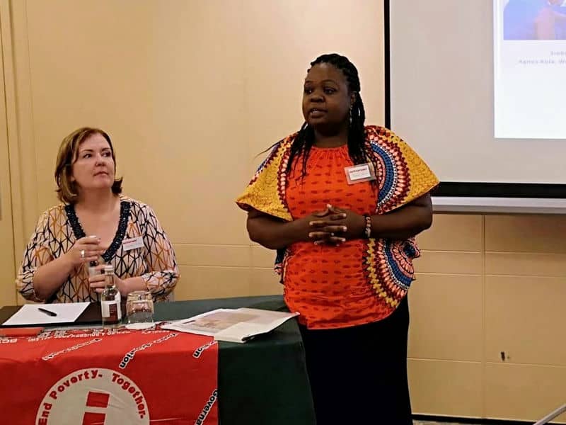 Two women presenting at a conference on poverty awareness, with a focus on collaborative solutions.