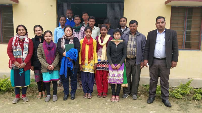 Group of people posing together in front of a building, showcasing diverse attire and friendly expressions.