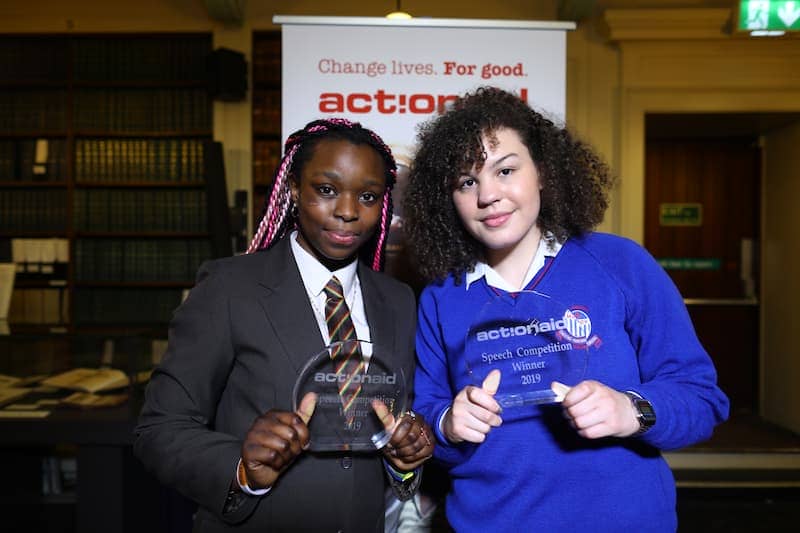 Two students holding awards at ActionAid speech competition, celebrating 2019 winners.