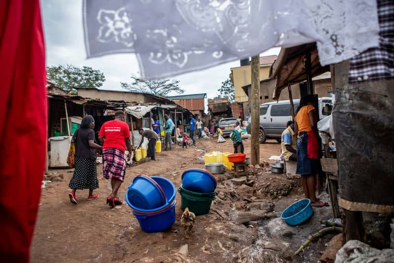 Busy street scene with people and colorful buckets in a local market setting, showcasing daily life dynamics.