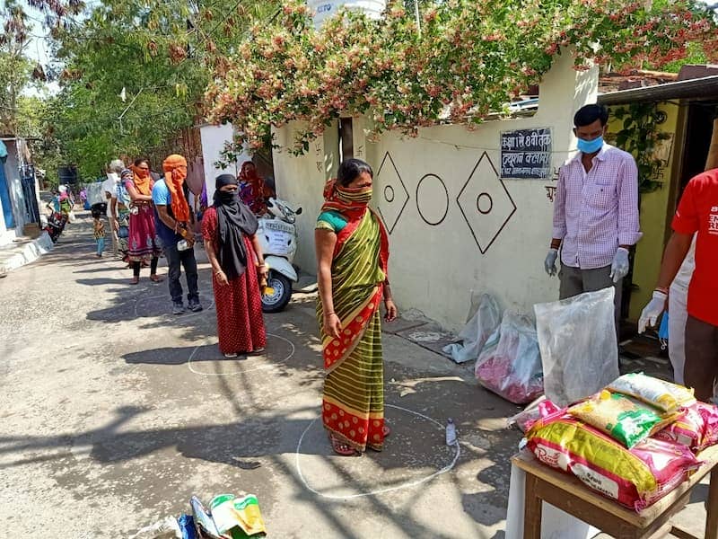 People in line with social distancing for food supplies during a distribution event in a community setting.