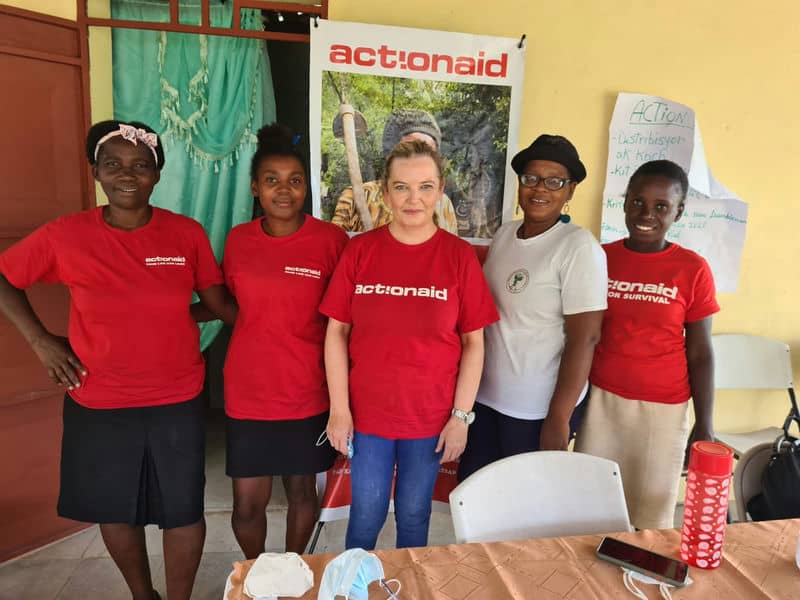 Group of people in ActionAid t-shirts at a community event indoors.