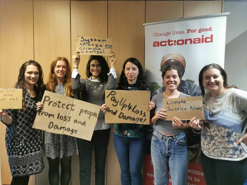Group of activists holding climate change signs at an ActionAid event for loss and damage advocacy.