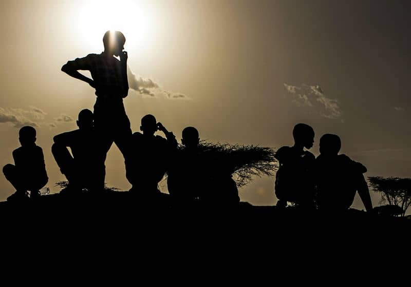 Silhouetted group of people at sunset on a hill, conveying unity and contemplation against a vibrant sky.