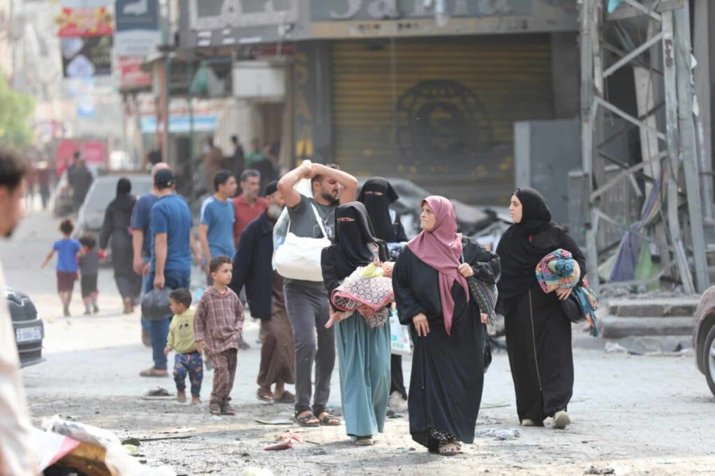 People walking in a city street, carrying packages and engaging in daily activities. Urban life scene.