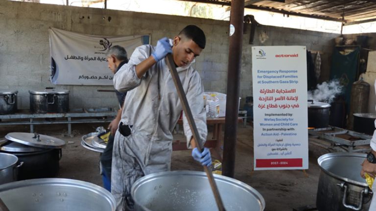Person cooking in a large kitchen for an emergency response program in Southern Gaza Strip.