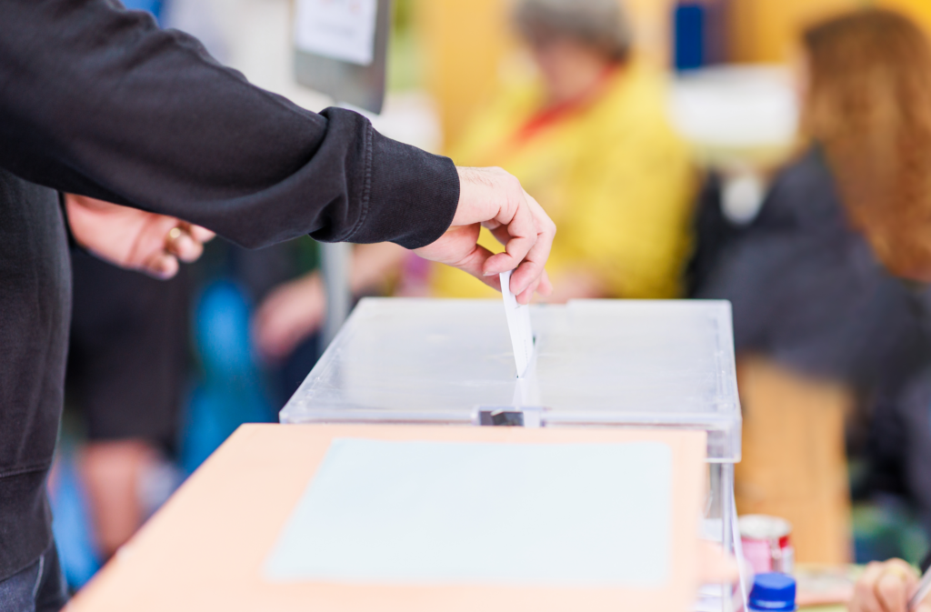 Person casting vote in a ballot box during an election, showcasing democratic participation and civic duty.