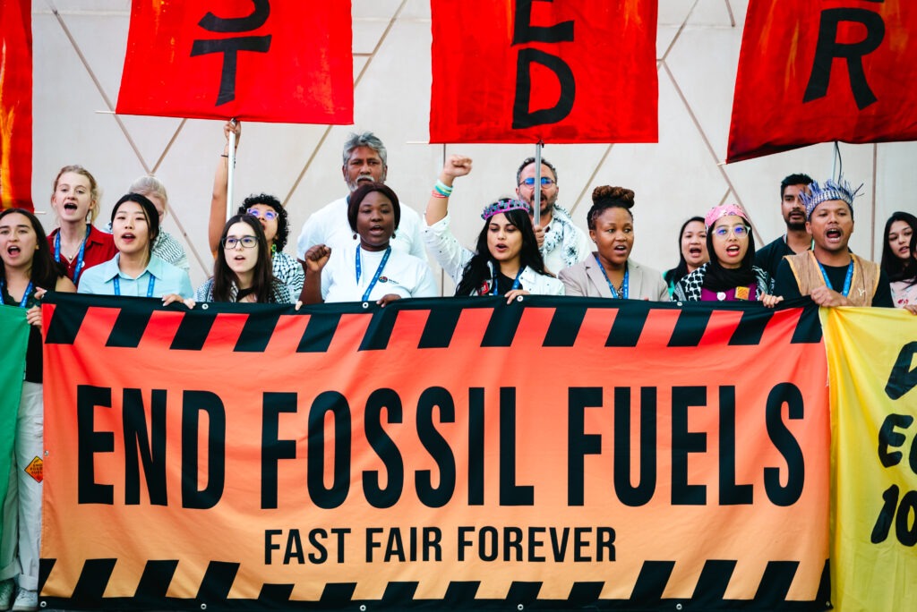 Protesters holding End Fossil Fuels banner at a climate demonstration, advocating for renewable energy solutions.