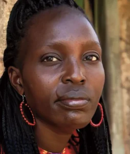 Portrait of a woman with braided hair and red earrings, looking thoughtfully into the distance.