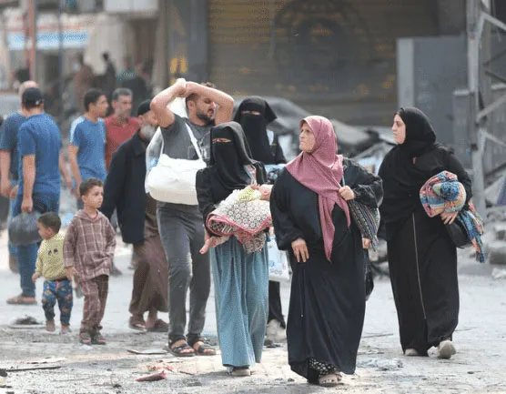 People walking through a war-torn street carrying belongings, depicting resilience and survival amidst crisis.