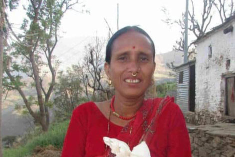 Woman in red sari holding fresh white mushrooms outdoors in a rural setting.