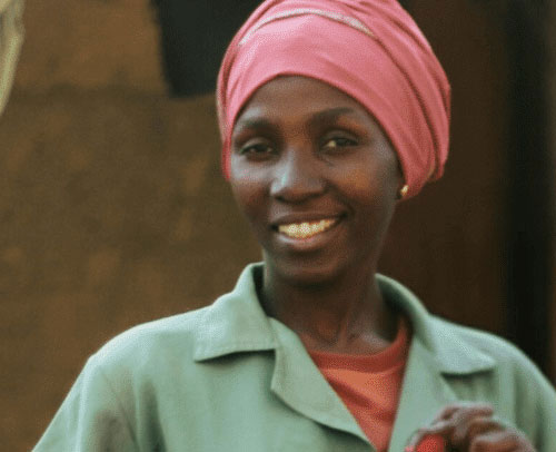 Smiling woman in work attire holding a tool, promoting women in skilled trades.
