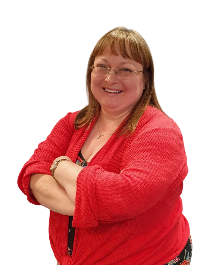 Smiling woman in a red cardigan with arms crossed against a white background.