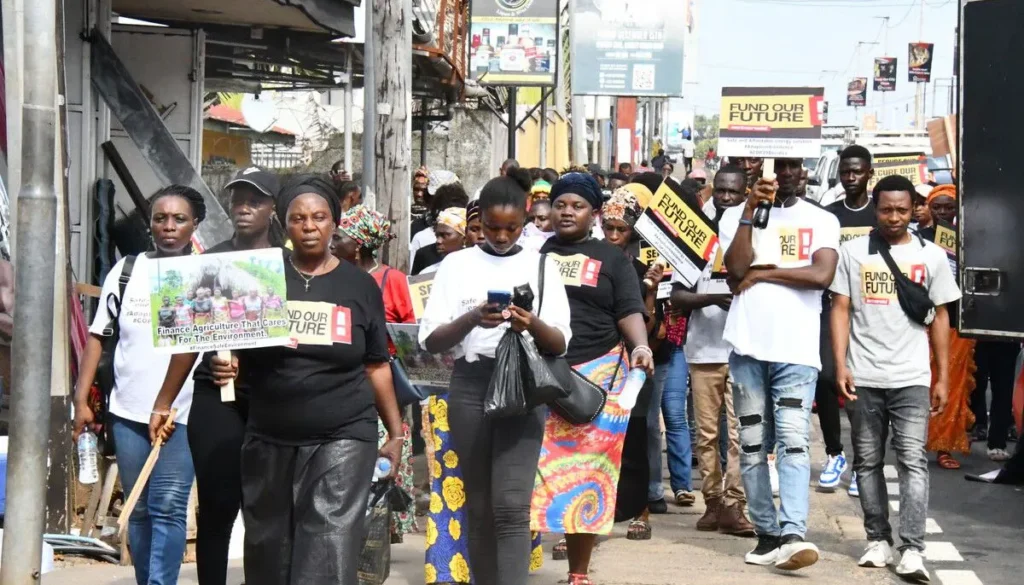 Protesters march for sustainable farming, holding signs advocating finance for environmentally-friendly agriculture.
